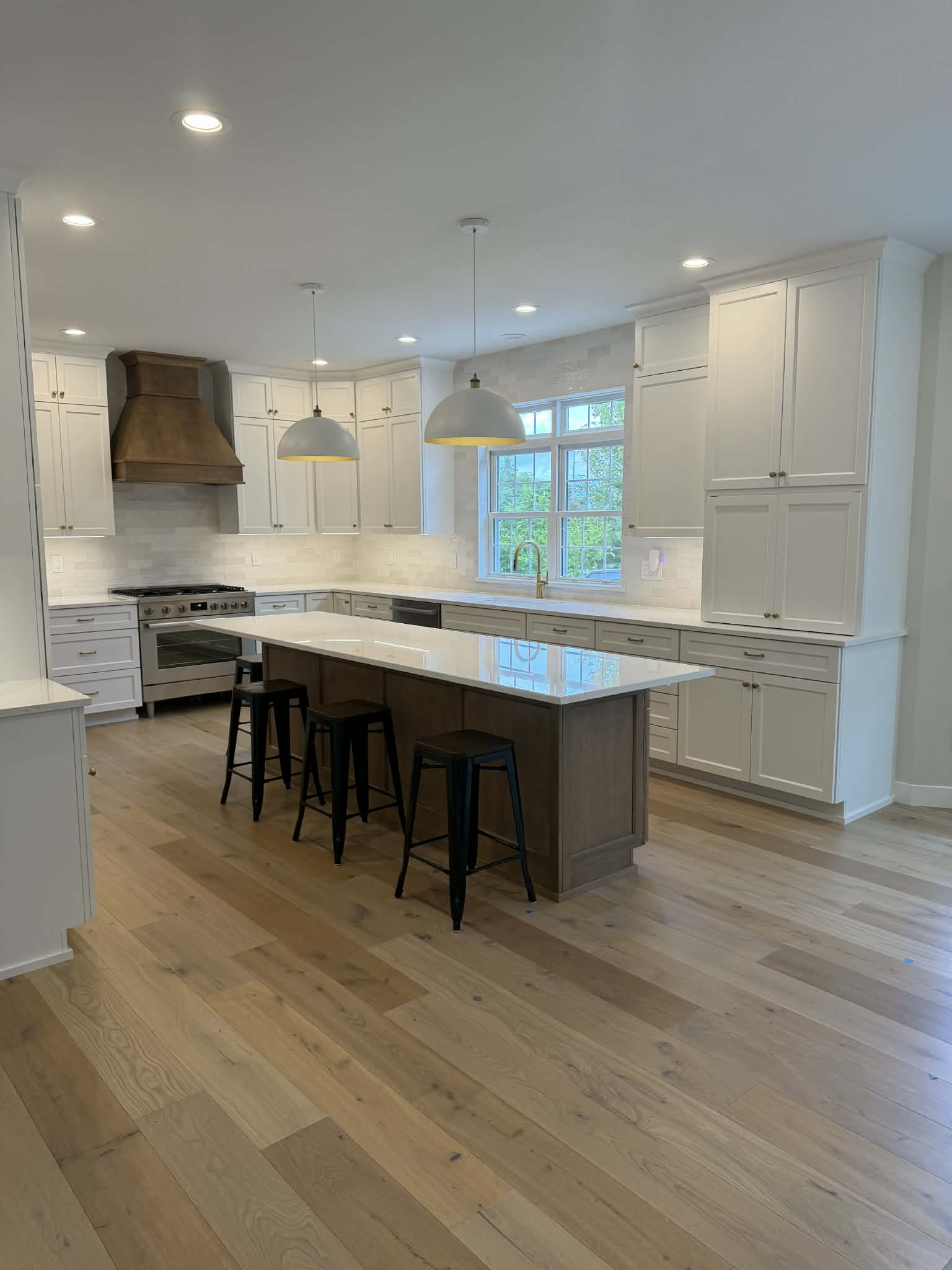 White kitchen with stained island, custom range hood, and pendant lighting