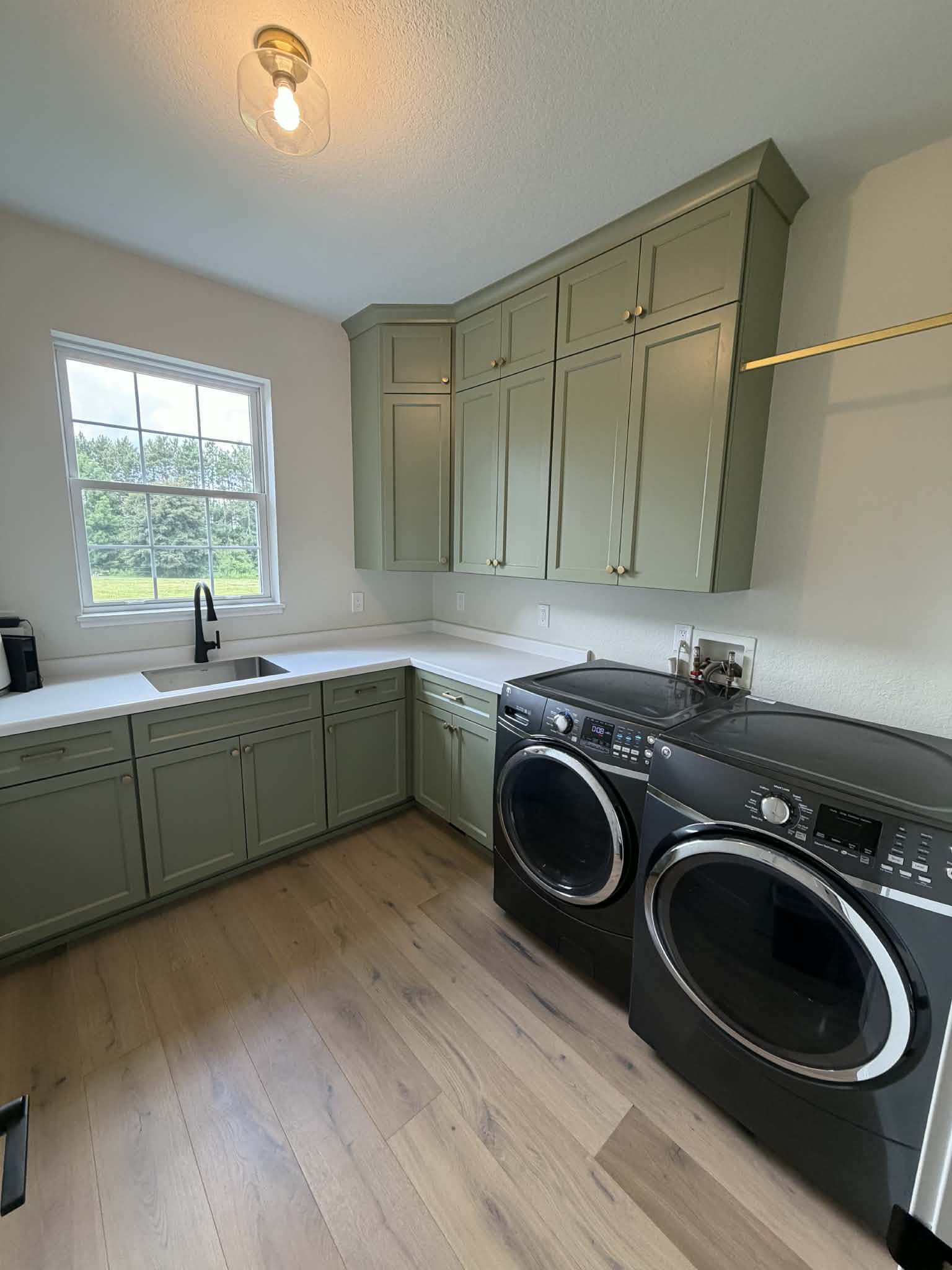 Custom sage green laundry room cabinetry with quartz countertop