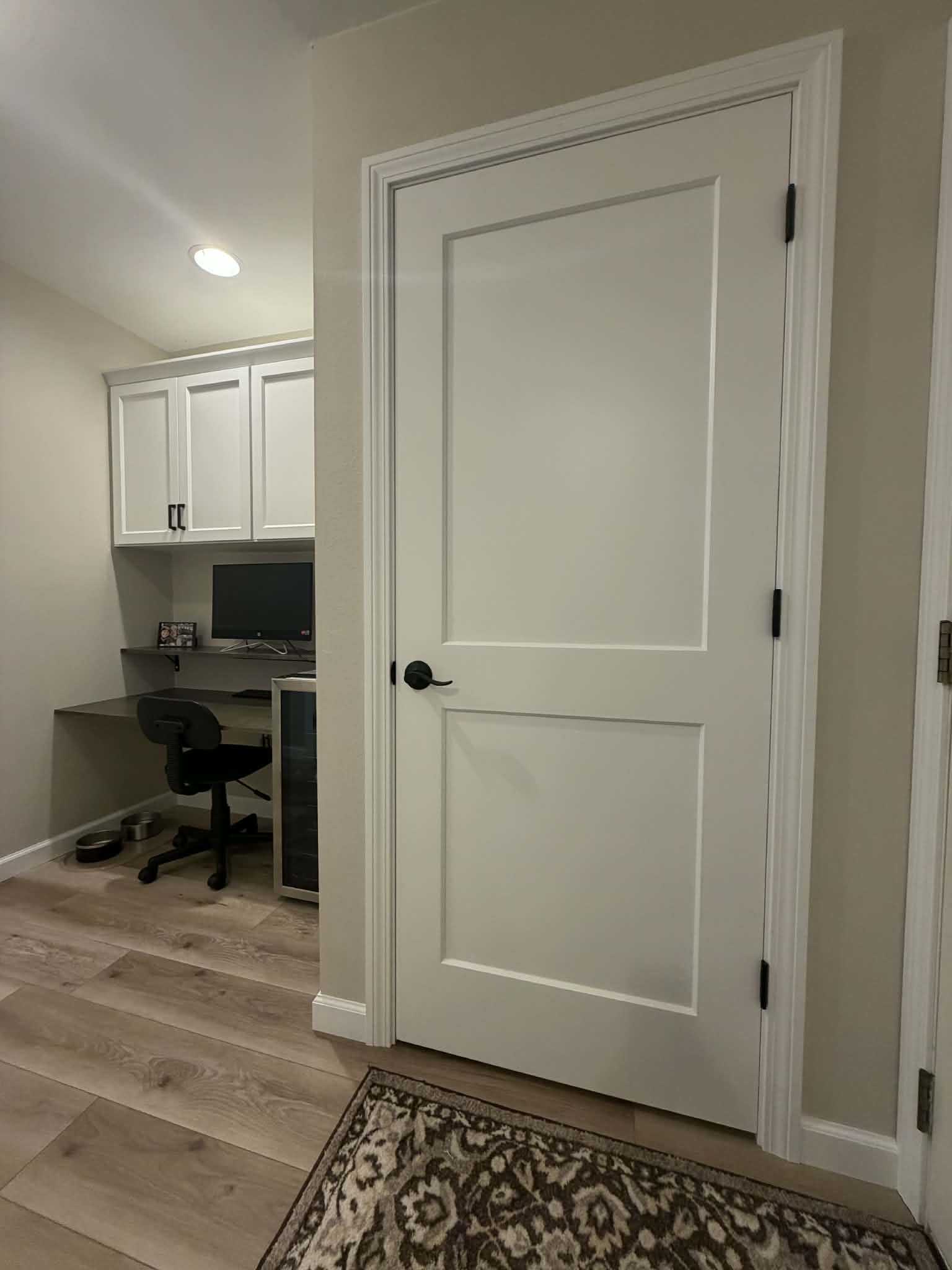Built-in desk nook with white cabinetry and custom door