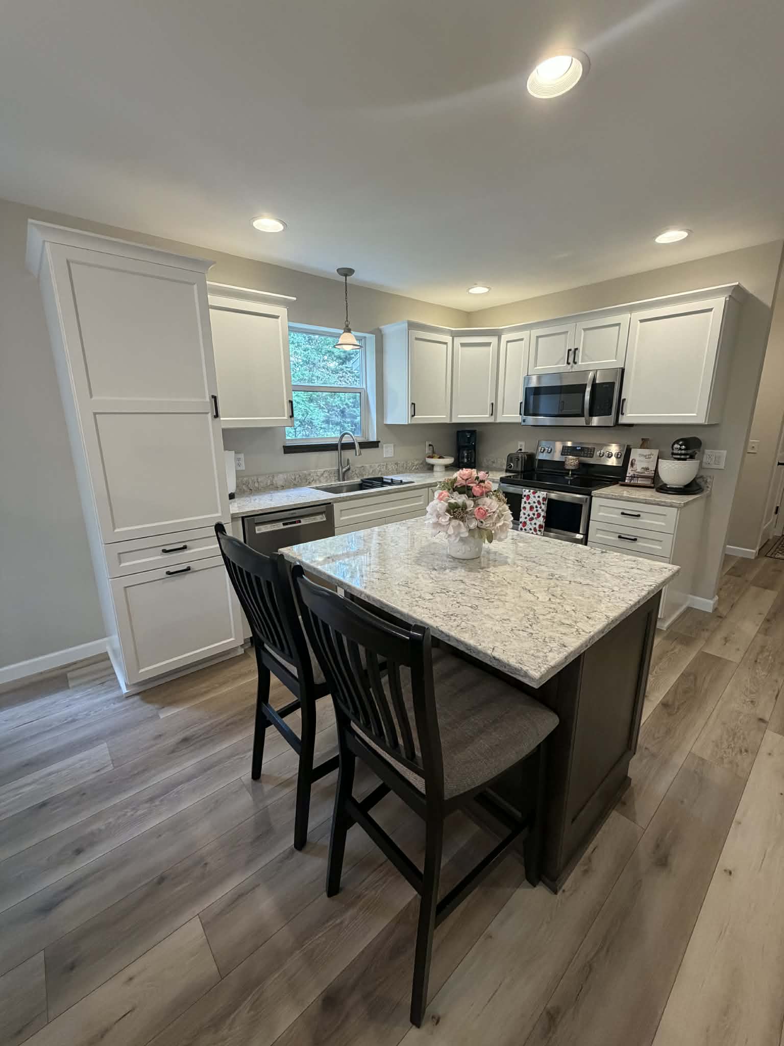 White kitchen cabinetry with granite island and seating